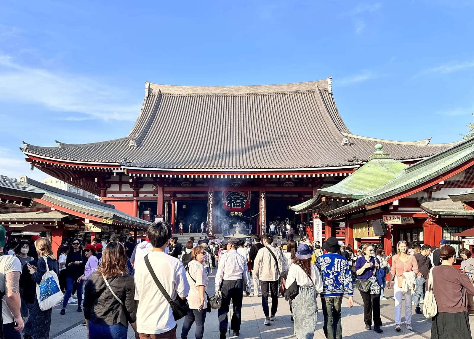 青空の下に建つ浅草寺本堂と参拝客