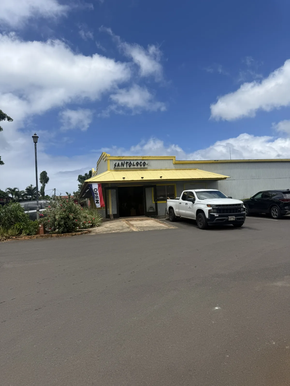 青空の下に黄色い屋根とSantoLocoの看板が見えるハレイワの店舗外観