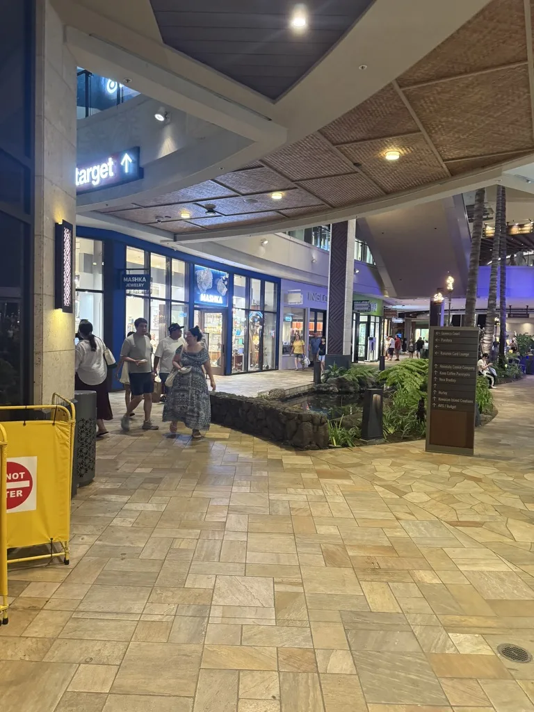 ショップと植栽が並ぶ夜のインターナショナル・マーケットプレイス館内通路